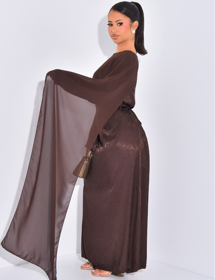 Langes, gemustertes Kleid, das im Rücken tailliert ist und an den Schultern ein Cape hat.