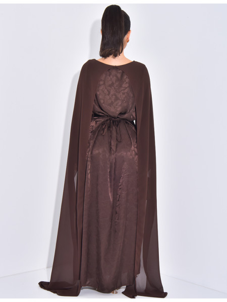 Langes, gemustertes Kleid, das im Rücken tailliert ist und an den Schultern ein Cape hat.