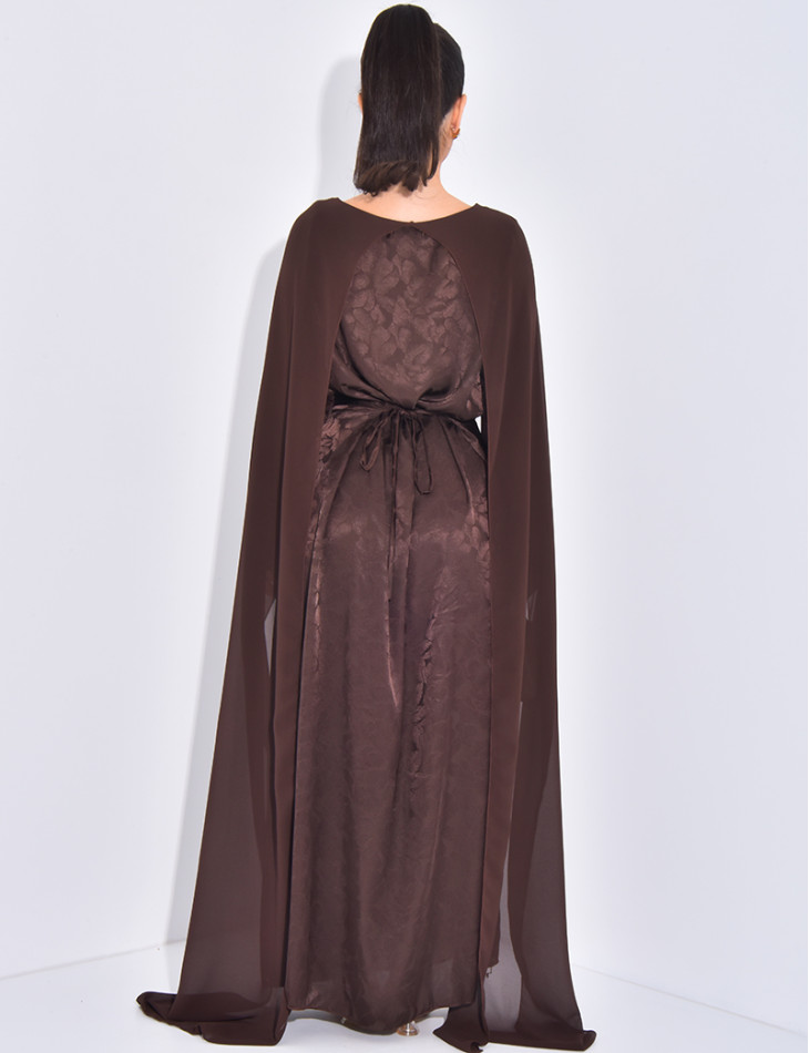 Langes, gemustertes Kleid, das im Rücken tailliert ist und an den Schultern ein Cape hat.