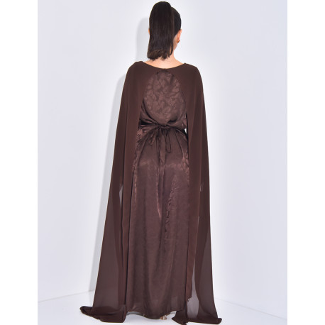 Langes, gemustertes Kleid, das im Rücken tailliert ist und an den Schultern ein Cape hat.