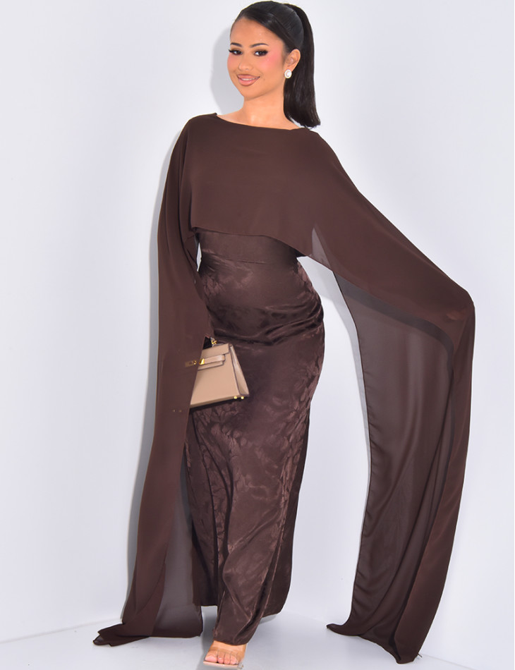 Langes, gemustertes Kleid, das im Rücken tailliert ist und an den Schultern ein Cape hat.